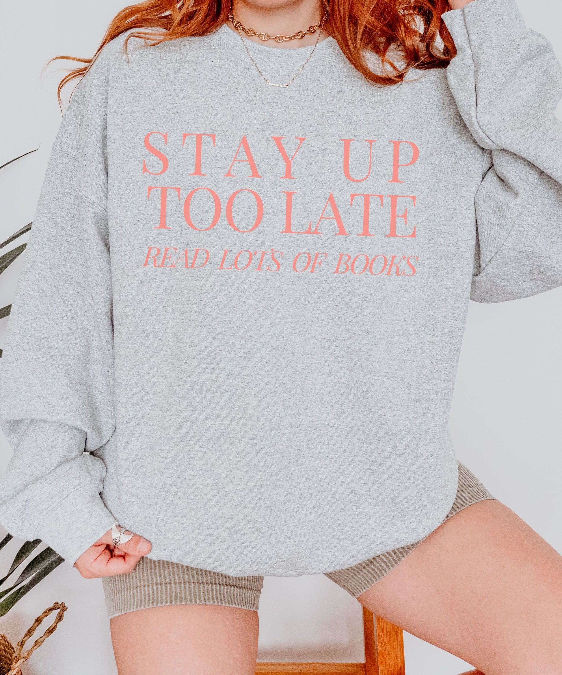 A crewneck sweatshirt that says "Stay up too late read lots of books" Available in Dark Green or peach Text in a minimal design.