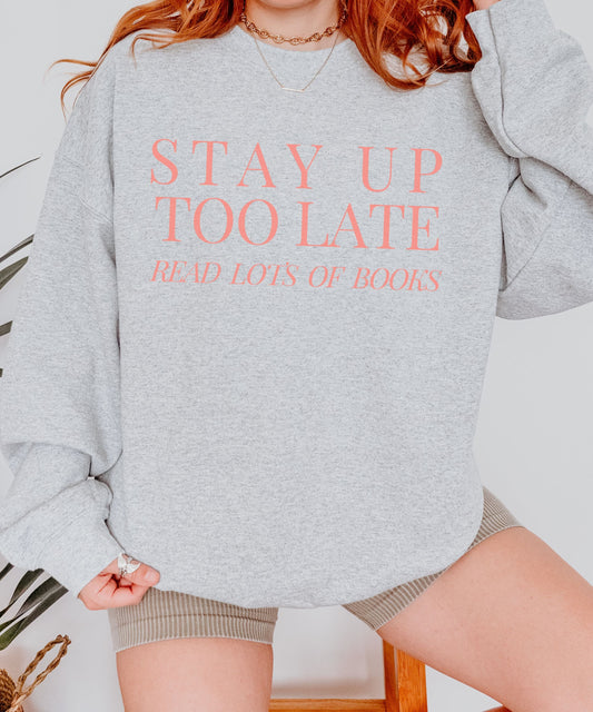 A crewneck sweatshirt that says "Stay up too late read lots of books" Available in Dark Green or peach Text in a minimal design.